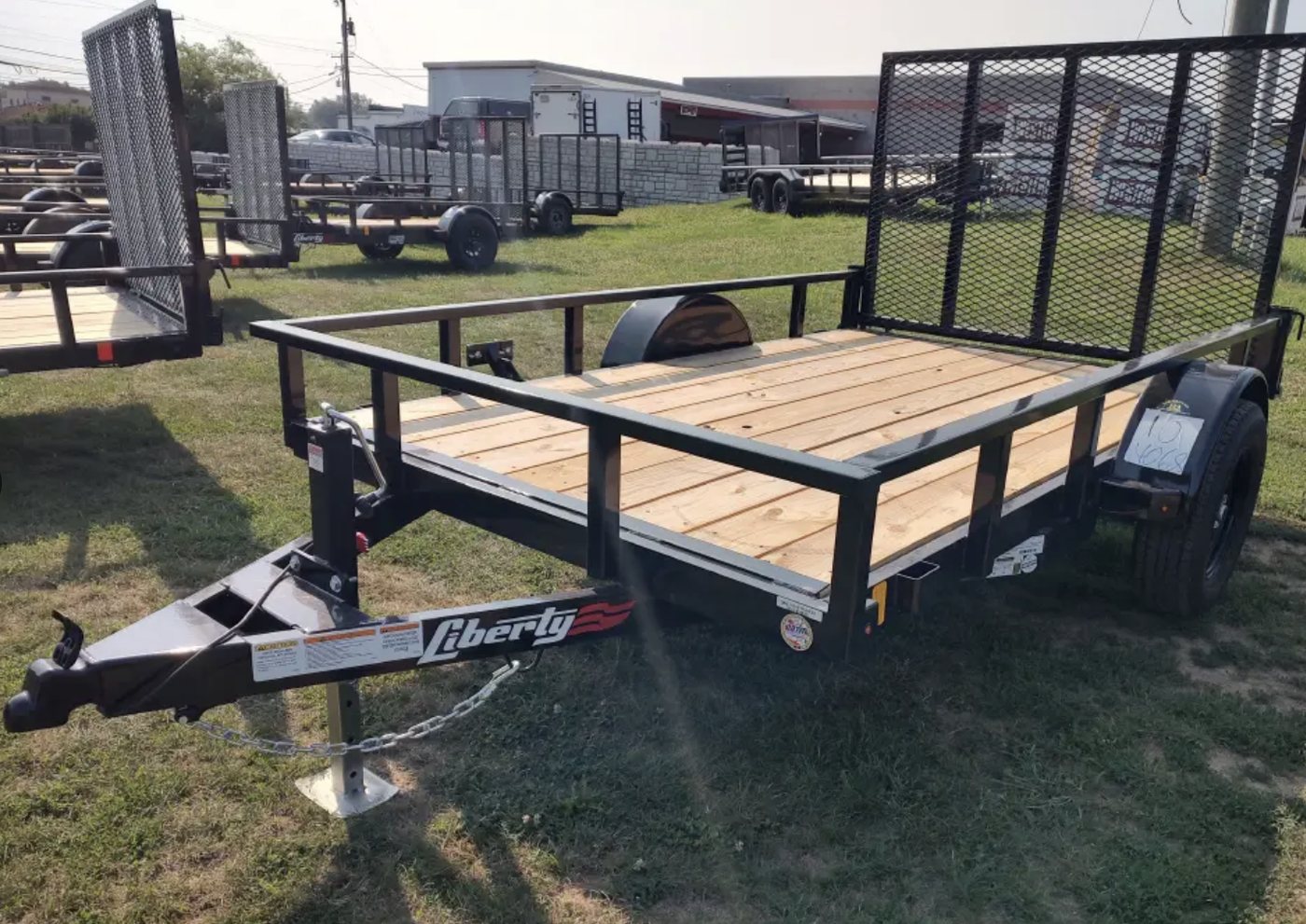 Black open utility trailer with a wood deck and rear gate
